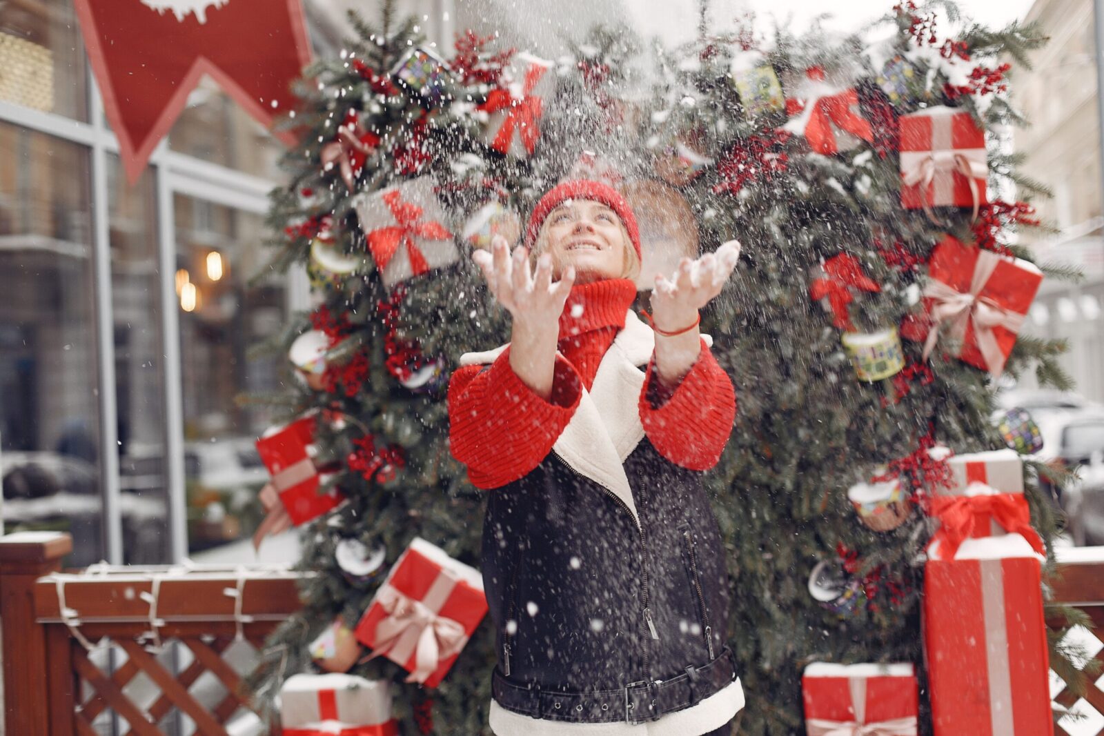 A woman joyfully plays in the snow with Christmas decorations creating a festive atmosphere.